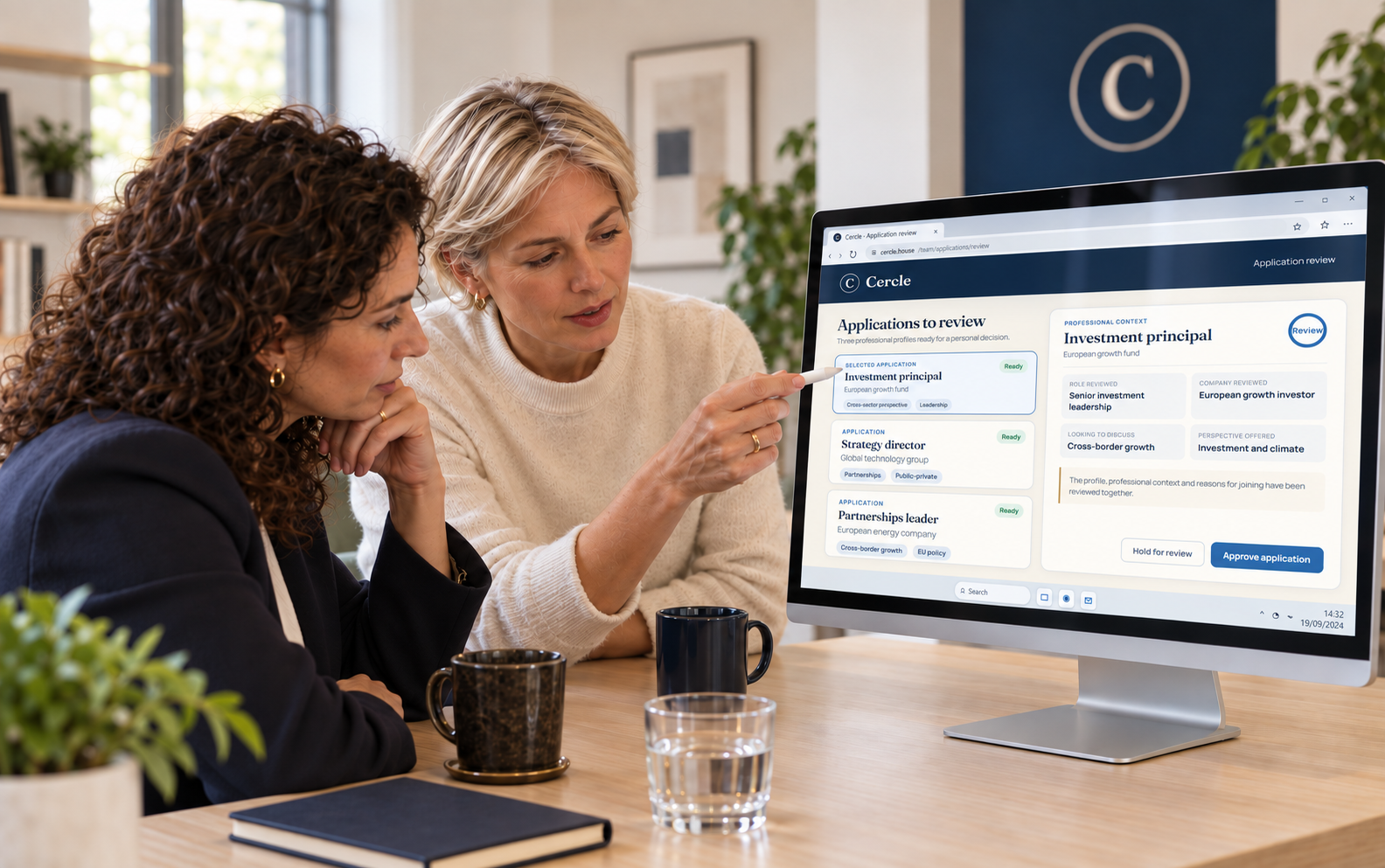 Two Cercle team members reviewing professional applications together on a desktop monitor